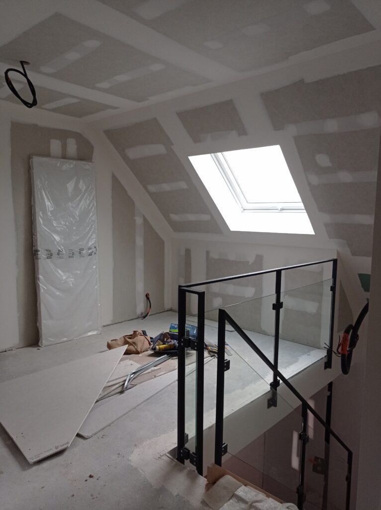 Aménagement sous combles en plaques de plâtre, avec fenêtre de toit et trémie d’escalier