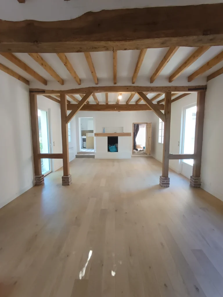 Parquet en chêne massif posé dans une pièce à poutres apparentes, pendant les finitions