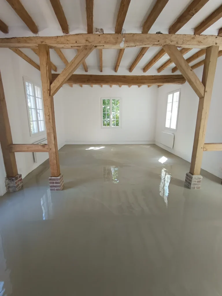 Support préparé dans une pièce avec poutres apparentes avant la pose du parquet
