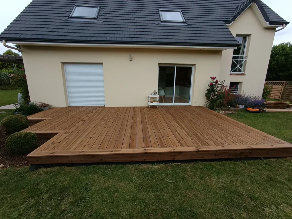 Vue de face d’une terrasse en pin devant les baies vitrées d’une maison